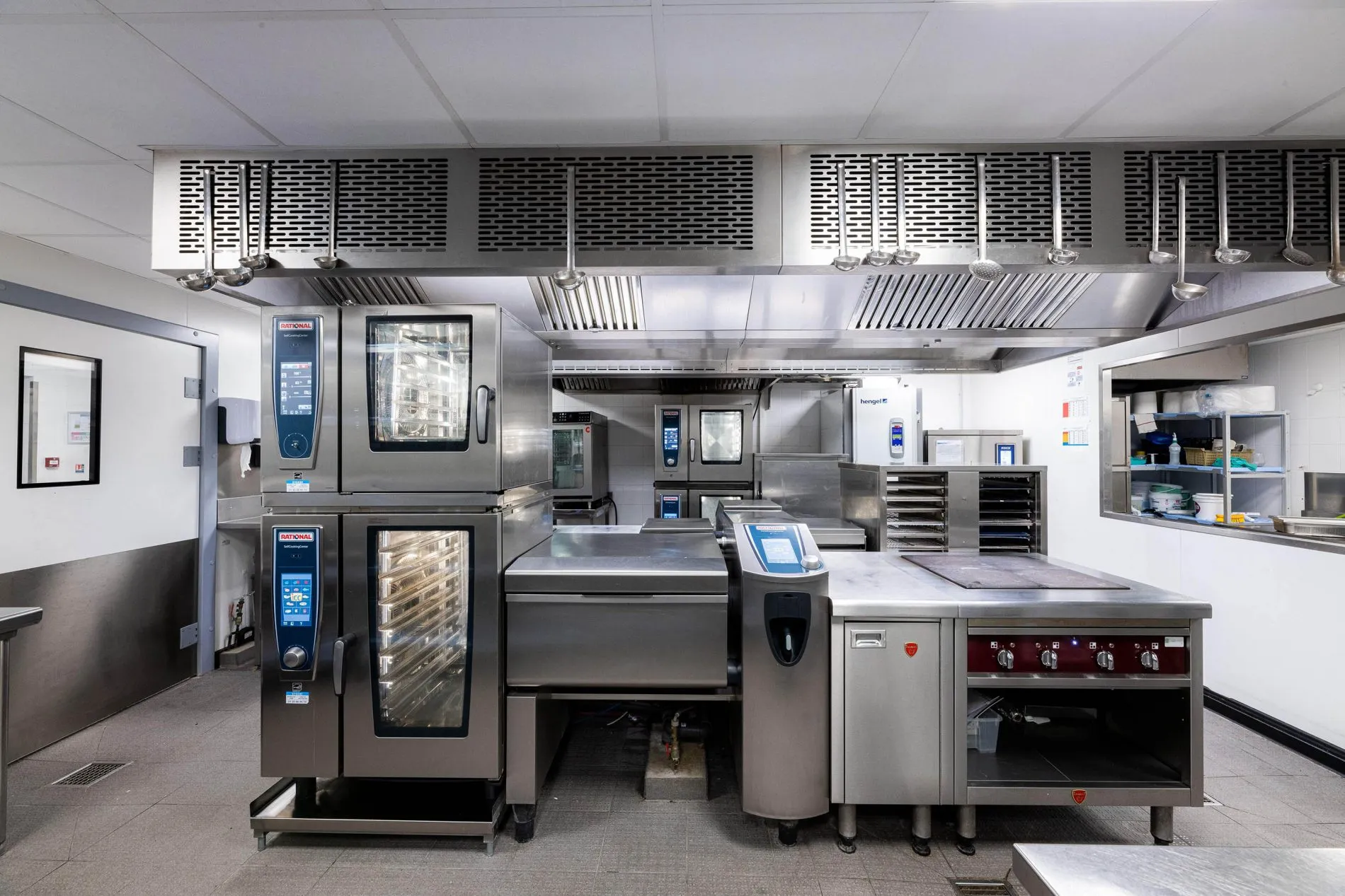 Cuisine professionnelle en inox, avec fours mixtes, sauteuse et plans de cuisson